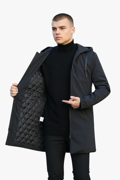 Man holding a black quilted coat against a white background