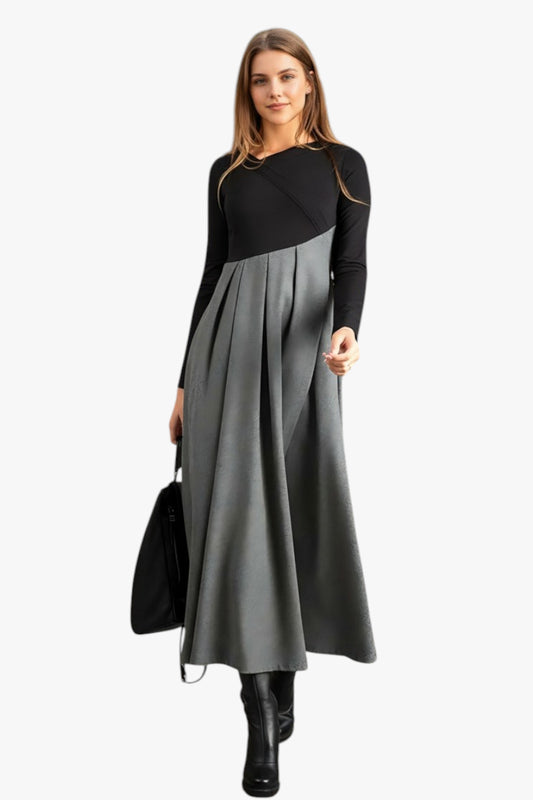 Woman wearing a black and gray dress holding a black handbag on a white background