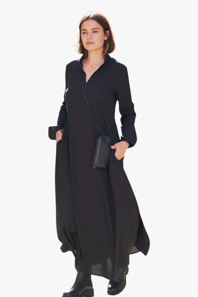 Woman wearing a long black dress with a plain background