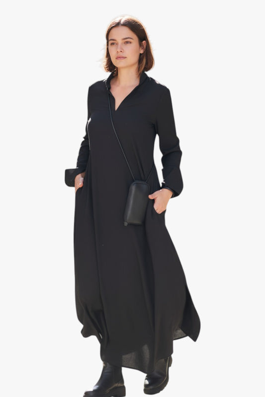 Woman wearing a long black dress with a plain background