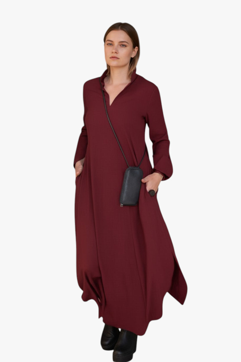 Woman wearing a burgundy dress holding a black handbag on a white background