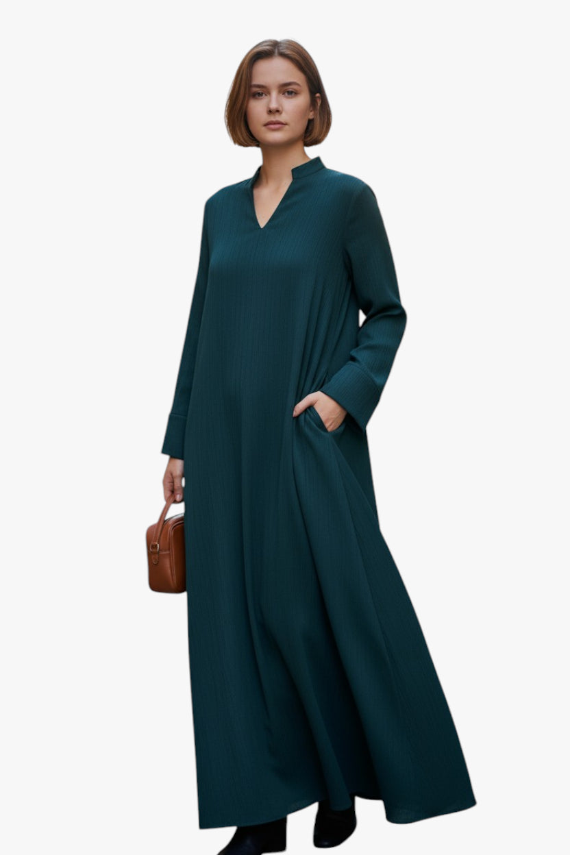 Woman wearing a teal dress holding a brown bag on a white background