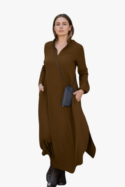 Woman wearing a brown dress holding a blue clutch against a white background