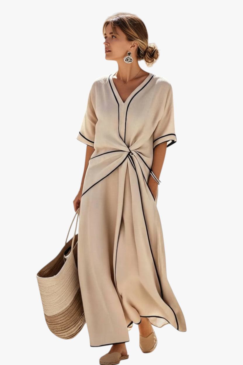 Woman wearing a beige dress with black trim, holding a straw bag on a white background