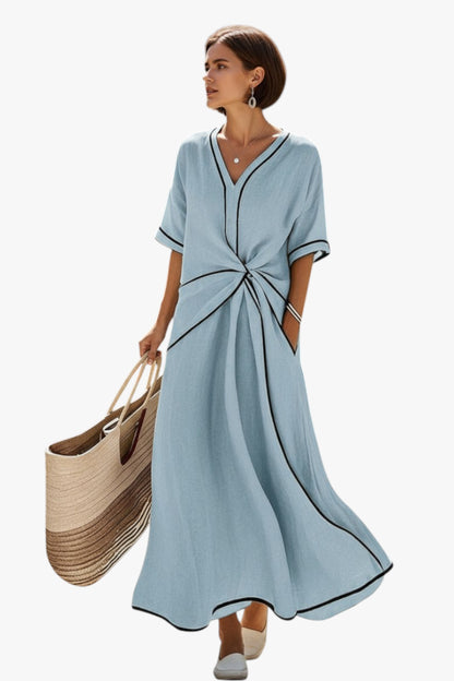 Woman wearing a light blue dress holding a woven bag on a white background