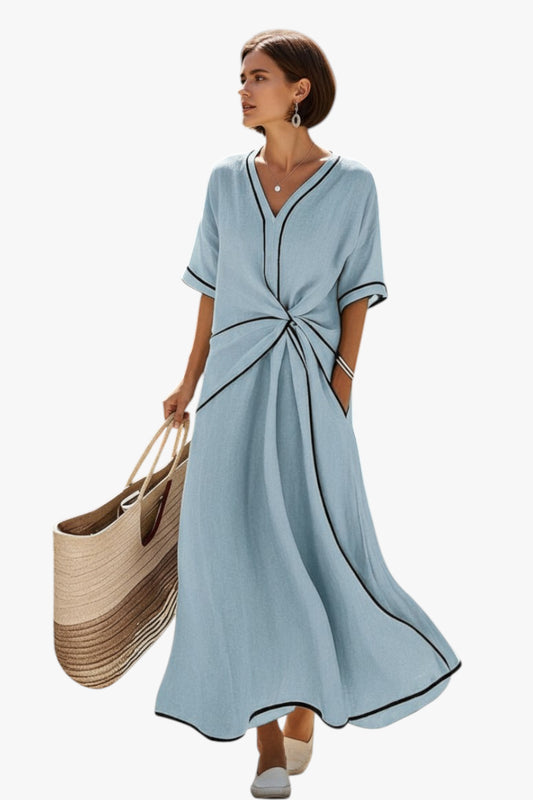 Woman wearing a light blue dress holding a woven bag on a white background